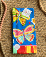 Colorful butterfly-themed towel with a tag on a textured surface