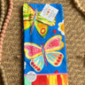 Colorful butterfly-themed towel with a tag on a textured surface